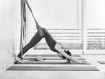 Tanja, Yoga Lehrerin und Expertin in Alignment Yoga, übt Adho Mukha Svanasana an der Yoga Wand im Yoga Studio in Zürich.