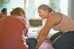 Zwei Teilnehmerinnen der Yogalehrer Ausbildung 2022 von the yoga place in Zürich erklären sich eine Übung. 