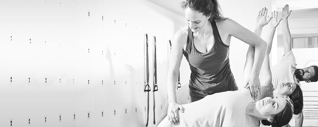 Tanja Lenger Mascarenhas von the yoga place korrigiert eine Teilnehmerin in Trikonasana im Yoga Studio in Zürich. 