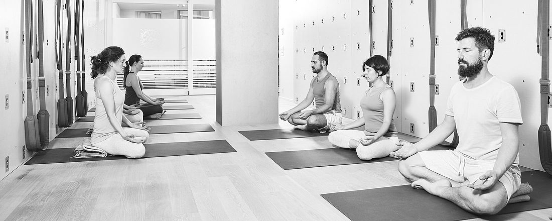 Teilnehmerinnen und Teilnehmer meditieren im Yoga Studio von the yoga place in Zürich.
