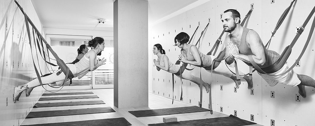Man sieht Teilnehmer und Teilnehmerinnen im Yoga Studio von the yoga place in Zürich an der Wand eine Übung machen.