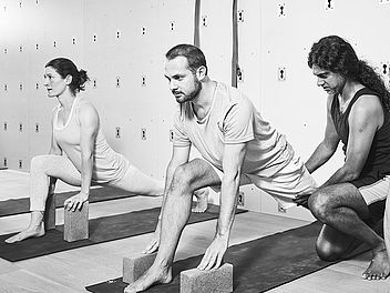 Joey, Yoga Lehrer und Experte in Alignment Yoga, korrigiert einen Schüler in Vanarasana im Yoga Studio in Zürich.